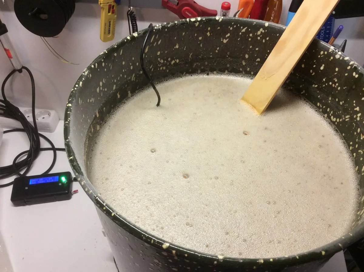 Schäumende Würze in einem alten Entsafter, daneben ein Holzpaddel