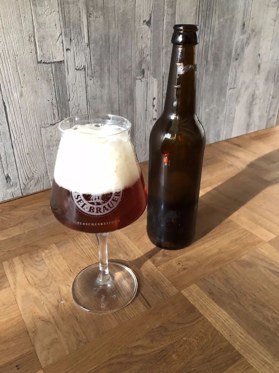 Dunkleres Bier im Glas neben einer braunen Flasche