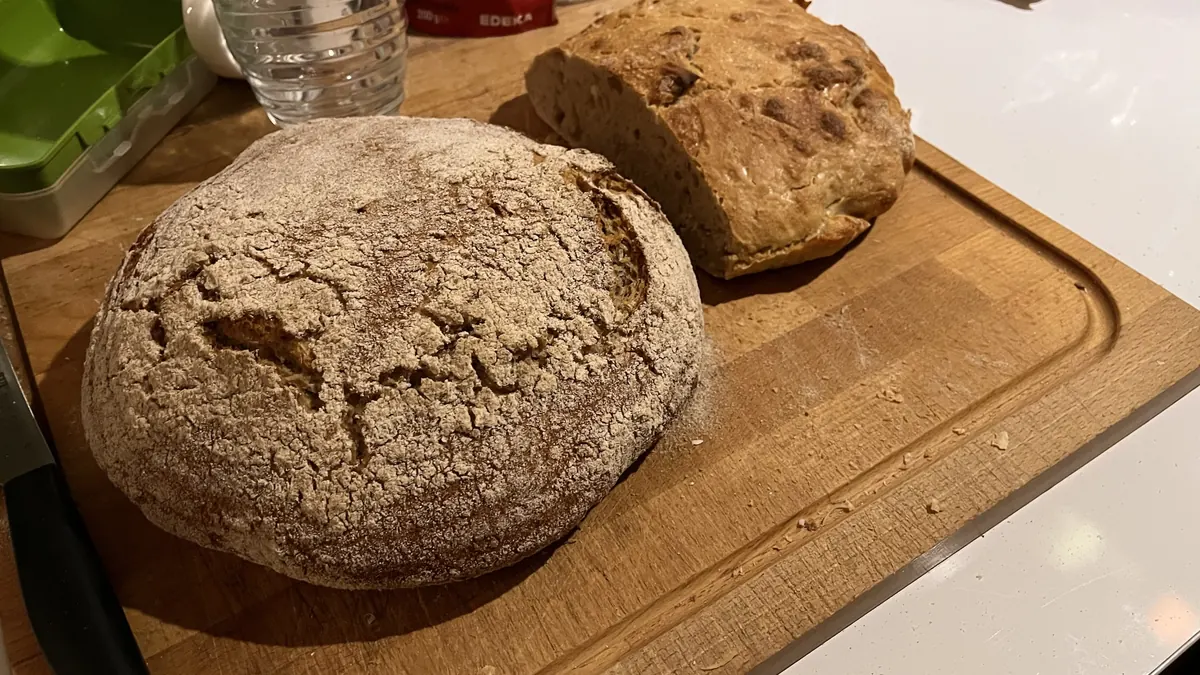 Zwei frisch gebackene Treberbrote auf einem Holzbrett